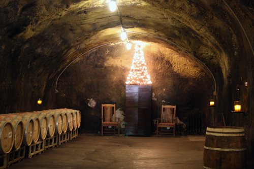 The warm glow of a Christmas tree lights the way inside the ancient Beringer Vineyards wine caves.