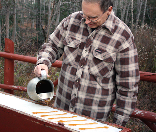 Maple syrup being poured on a bed of snow.