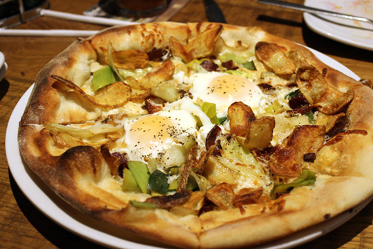 A pizza with bacon, eggs and potatoes.