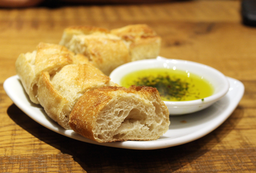A crusty baguette with olive oil is brought to the table.