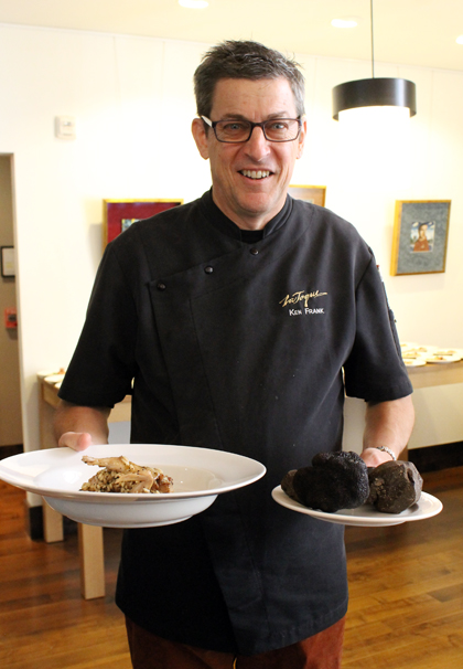 Chef Ken Frank holding a plate of black truffle risotto with quail that was made in a demo by Chef Roberto Donna.