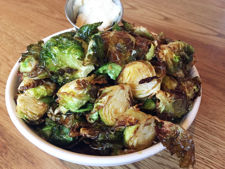 A bowl laden with fried Brussels sprouts.