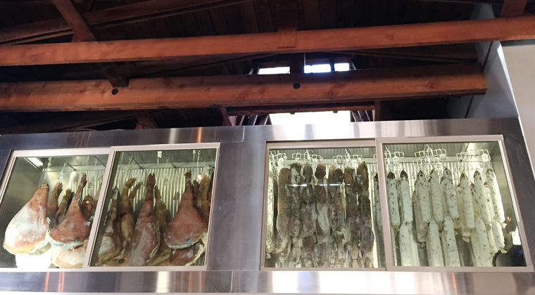 Refrigerator cases of house-made charcuterie hanging above the kitchen.