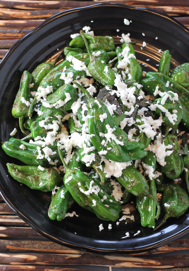 A pile of just-seared shishitos gets dressed with lovely goat cheese and sage leaves.