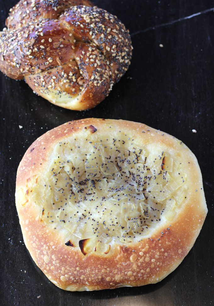 A chewy-good bialy (foreground), and an "Everything Knot'' (back) with a fluffy texture and taste of onion, garlic, poppy seeds and sesame seeds.