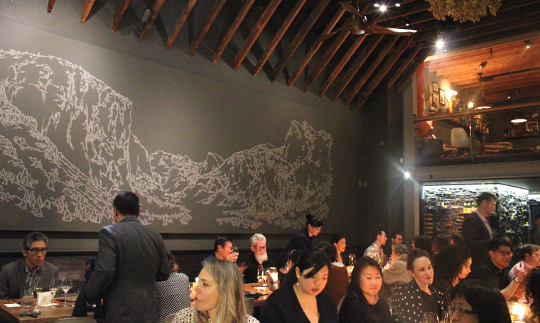 Guests fill up the two communal tables. A mural of Yosemite graces the wall.