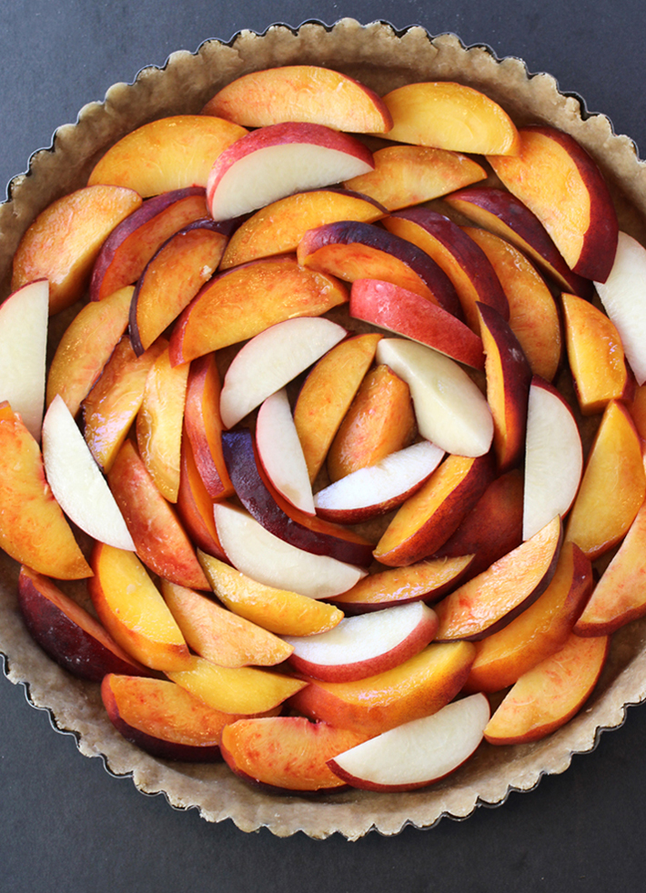 Peaches and one nectarine arranged in the crust before baking.