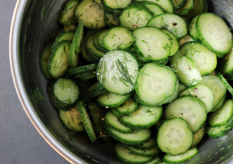 The sliced cucumbers tossed with the pickling ingredients.