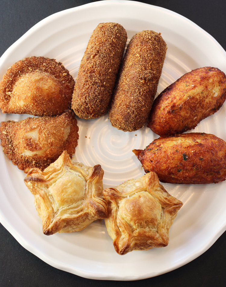 The assortment of savory items (clockwise from top): meat croquettes, codfish cakes, chicken pot pies, and shrimp turnovers.