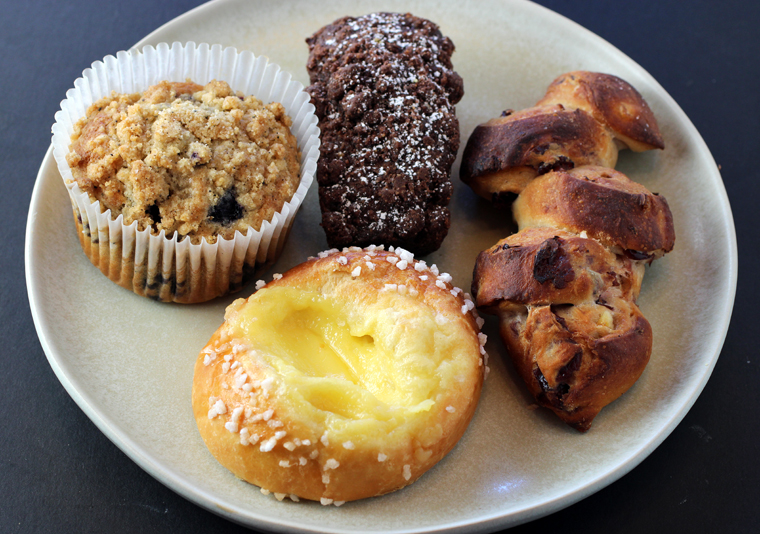 (Clockwise from top): Cocoa carrot cake, cranberry-orange epi, Meyer lemon brioche, and blueberry cornmeal muffin.