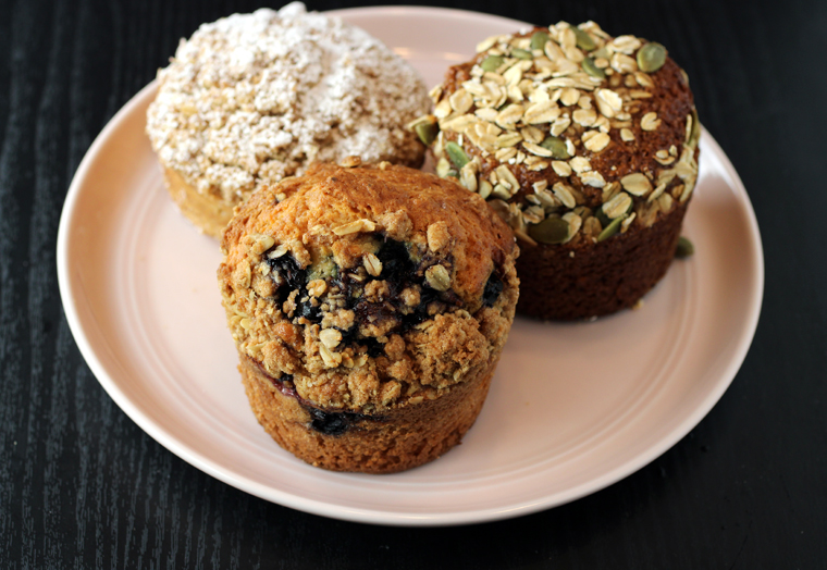 Blueberry muffin front and center, flanked by a coffee cake and a bran muffin.