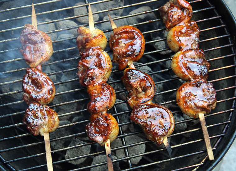 The skewers getting charred and smoky on the grill.