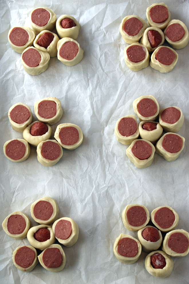The sliced dough-wrapped hot dogs are arranged in a flower shape on a baking sheet.