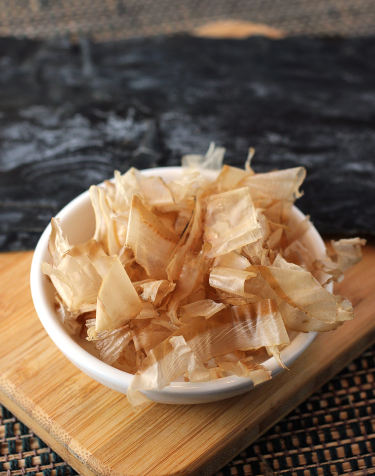 Bonito flakes (shaved, dried, smoked and fermented skipjack tuna) in the foreground, and kombu (dried kelp) in the background.