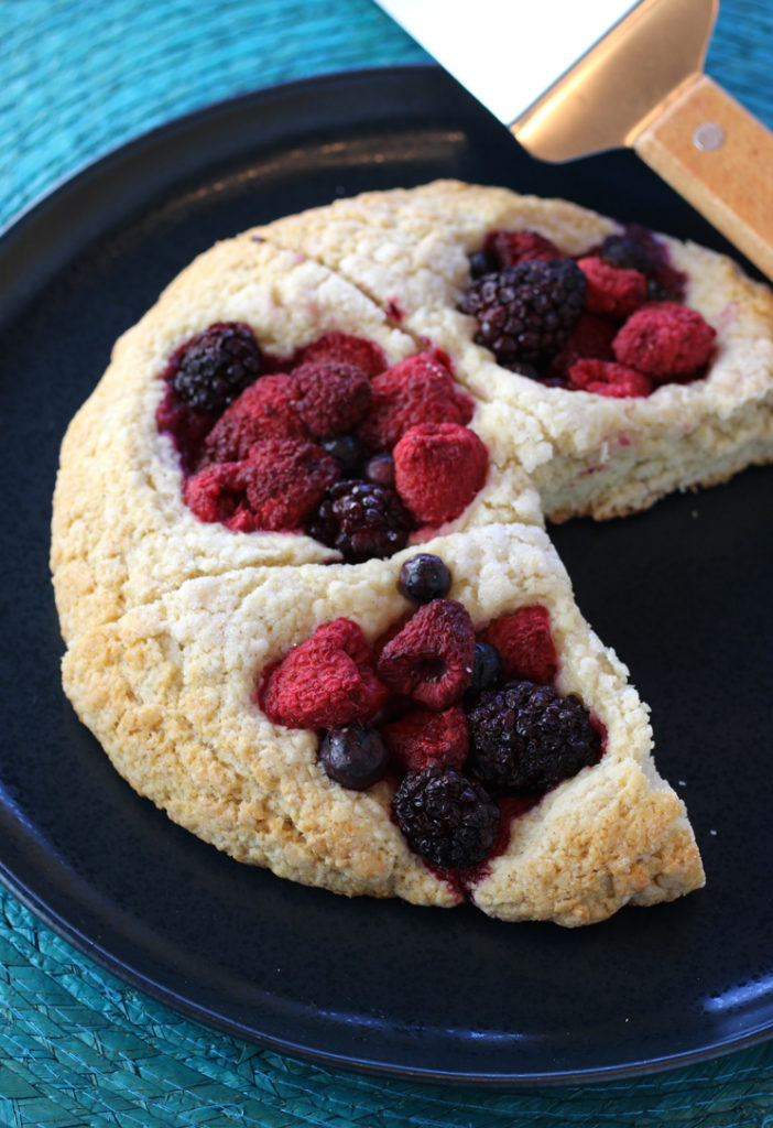 Holes get punched into a big round of biscuit dough, then filled with fresh berries, before being baked.