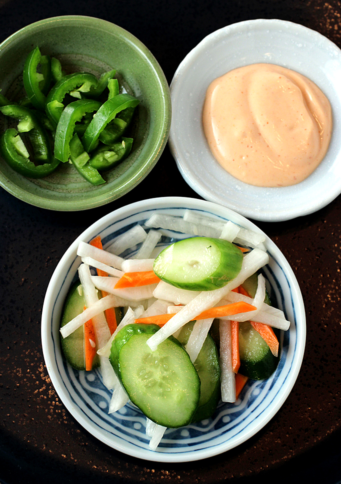 Toppings for the burger (clockwise from top left): sliced jalapenos, sriracho mayo, and quick-pickled veggies.
