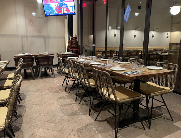 The outdoor dining space features motorized screens, and glass accordion doors that connect to the restaurant and can be opened completely in summer.