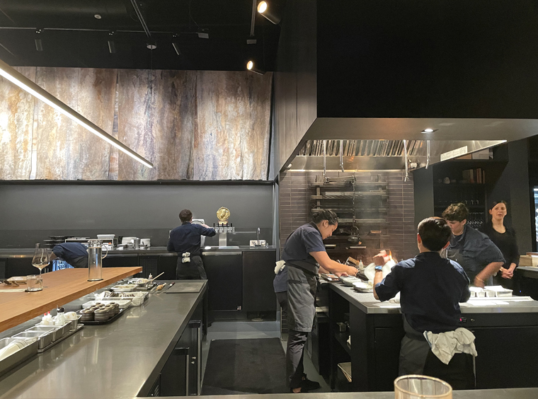 Diners are seated at the u-shaped counter that encircles the live-fire robata.