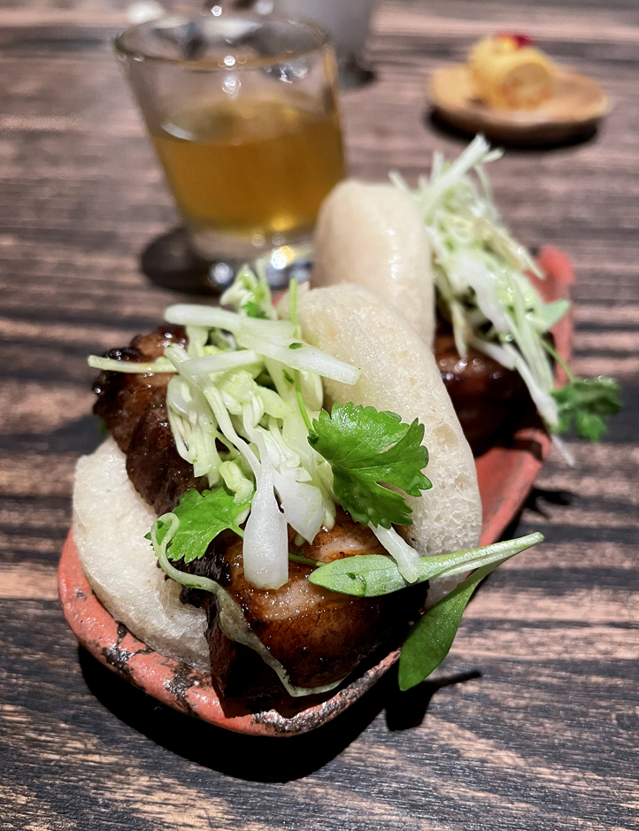 A trio of snacks, which includes these juicy pork belly buns, opens the meal at Madcap.