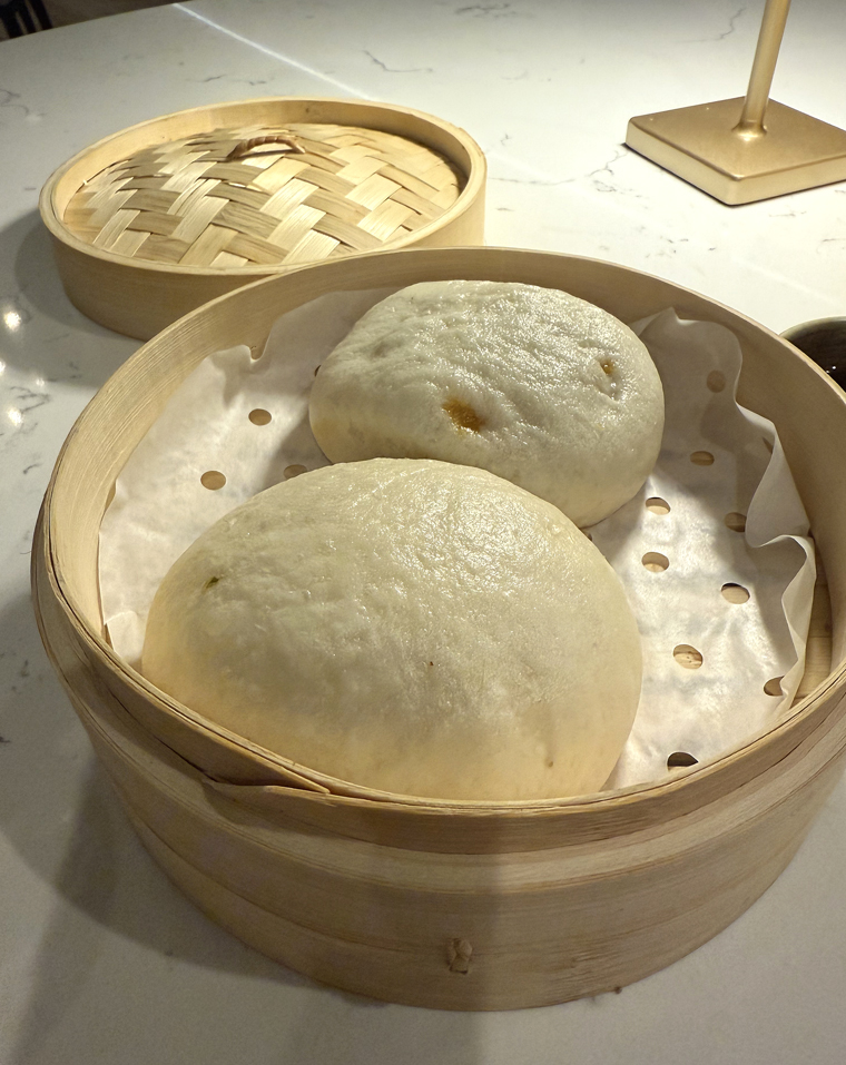 Lamb baos arrive fresh and hot in steamer baskets.