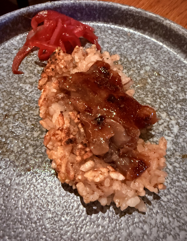 The rich marrow spread atop the flattened onigiri.